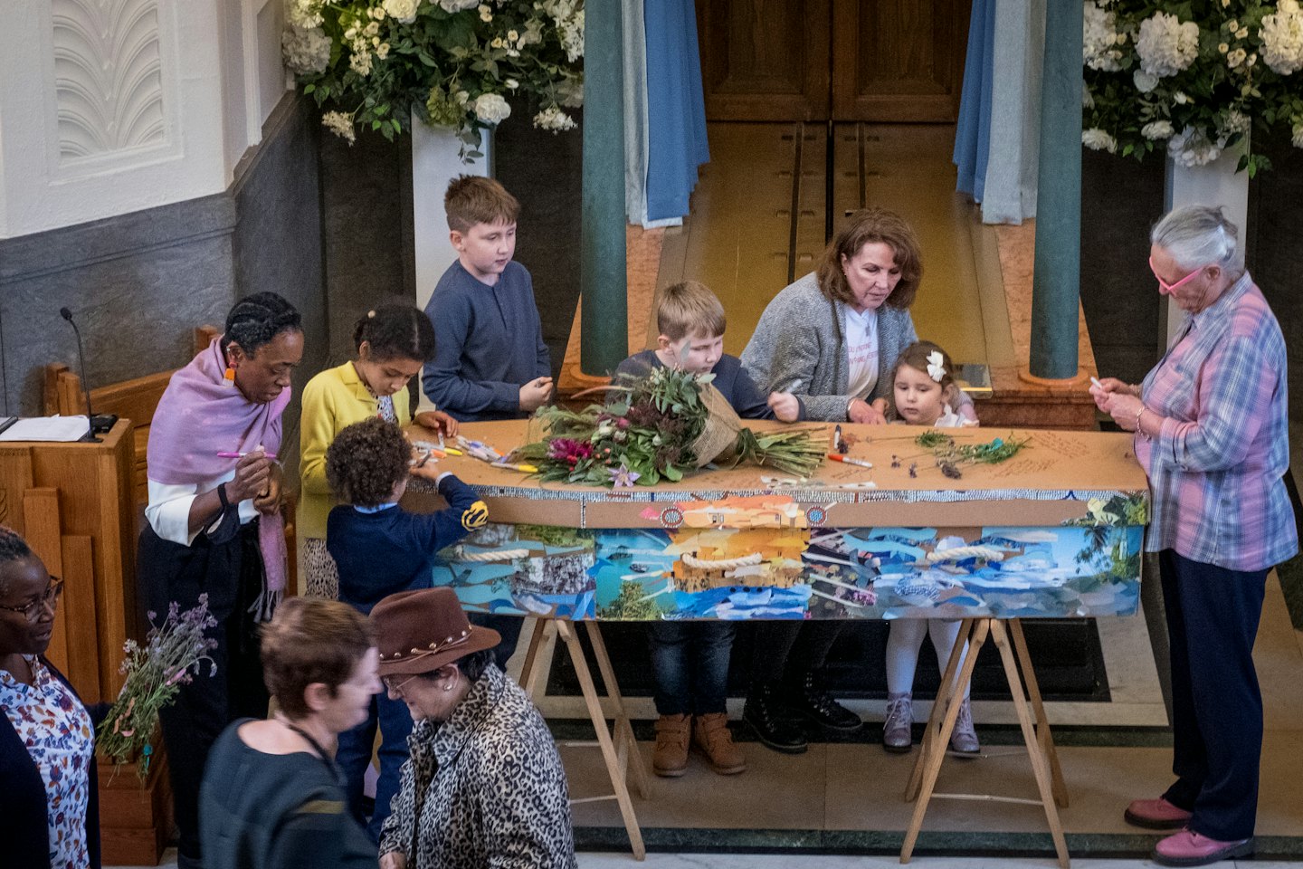 Diverse group of people creating art on a large table.